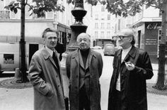 three men standing next to each other in front of a fountain