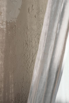 a cat sitting on top of a window sill next to a wall with peeling paint