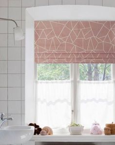 a bathroom window with pink roman shades and white tiles on the walls, along with two teddy bears