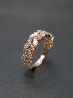 a gold and white diamond ring sitting on top of a black surface with diamonds in the middle