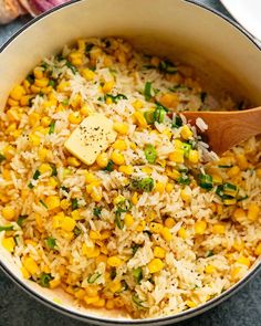 a pot filled with rice and corn on top of a table next to an onion wedge