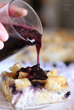 someone is pouring blueberry sauce on a piece of bread with croutons in the background