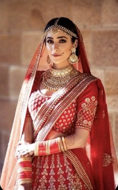 a woman wearing a red and gold bridal outfit