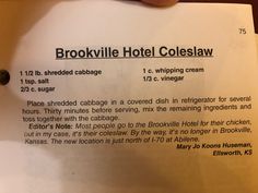 a person holding up a piece of paper with information about the hotel coleslaw