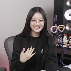 a woman sitting at a desk with her hands in the air