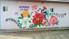 a painted mural on the side of a building with flowers and words written in spanish