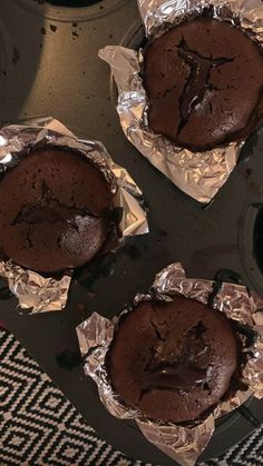 three chocolate muffins sitting on top of tin foil