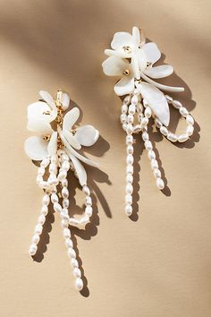 two white flowers and pearls are attached to the back of these earring sets,