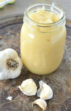 a jar filled with yellow liquid next to garlic