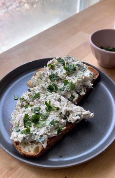 two pieces of bread with chicken salad on it sitting on a plate next to a bowl