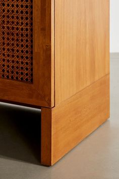 a wooden cabinet with an intricate design on the front and side panel, sitting on a gray surface