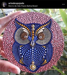 an owl painted on top of a pink and blue object in front of some plants