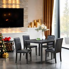 a dining room table with chairs and a christmas tree in front of the fireplace,