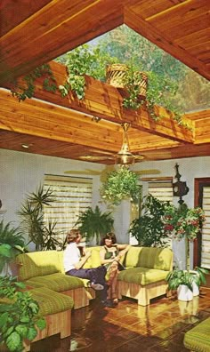 two people sitting on couches in a living room with plants and potted plants