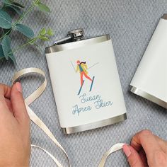 a person holding a white ribbon next to a flask with a skier on it