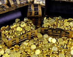 there are many gold coins in the box and on the floor, all stacked together