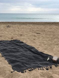 a black blanket laying on top of a sandy beach