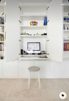 a white desk with a computer on it in a room filled with books and other items