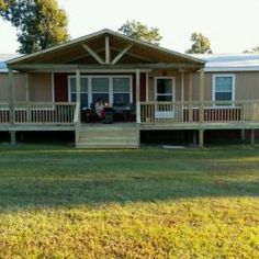 a mobile home sits in the middle of a grassy area with two cars parked on it