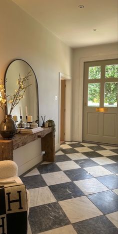 a hallway with black and white checkered flooring next to a large mirror on the wall