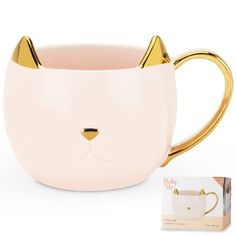 a pink and gold mug with a cat's face on the side, next to a card