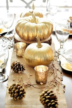 the table is set with pine cones and pumpkins