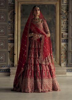 a woman in a red and gold bridal gown standing with her hands on her hips