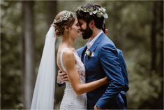 a bride and groom standing together in the woods