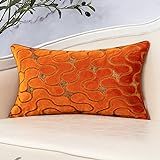 an orange decorative pillow on a white couch