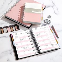 an open planner, pencils and other office supplies on a white marble countertop