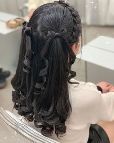 a woman sitting in front of a mirror with her hair styled into a pony tail