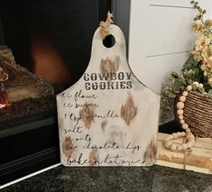 a wooden sign sitting on top of a counter next to a fire place and potted plant