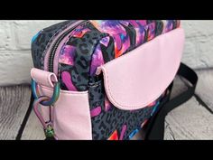 a pink and black leopard print purse on a wooden table with white brick wall in the background