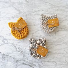 three small heart shaped candies with tags on them sitting on a marble counter top