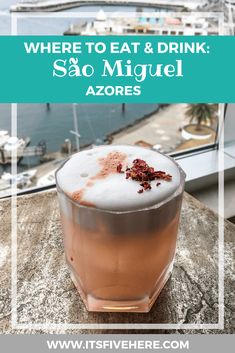 a drink sitting on top of a table next to the ocean