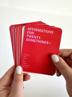 a person holding four red cards with the words affirmations for twenty somethings