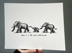 a hand holding up a piece of paper with an image of three elephants on it