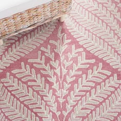 a pink and white rug on the floor next to a wicker basket