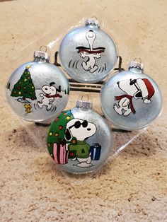 three glass christmas ornaments with snoopy characters on them