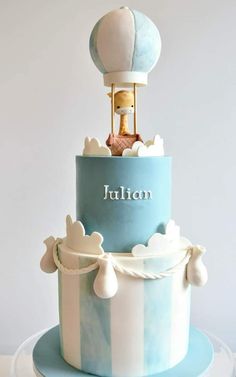 a blue and white striped cake with a hot air balloon on top that says julien