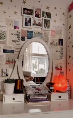 a white dresser topped with a mirror next to a wall covered in pictures and photos