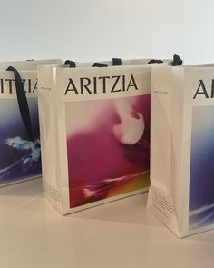 three shopping bags sitting on top of a table next to each other with the word artzza printed on them