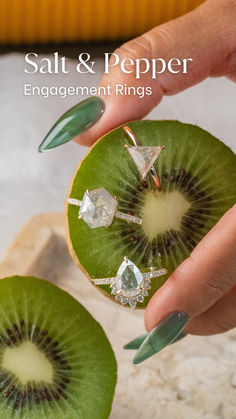 a person holding a piece of fruit with diamonds on it's fingers and nails