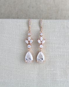 two pairs of earrings with white stones on the bottom and one pair in rose gold