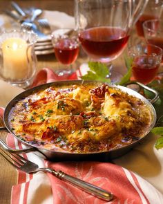 a plate with some food on it next to glasses of wine and utensils