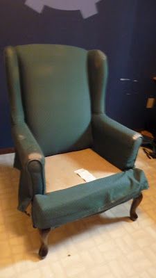 a green chair sitting on top of a tiled floor next to a blue painted wall