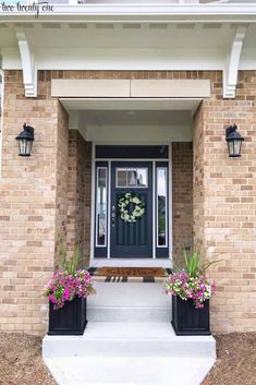 a front door with two planters on the steps and a wreath hanging above it