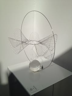 a glass sculpture sitting on top of a white table next to a bowl and lamp