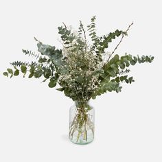 a vase filled with lots of white flowers and greenery