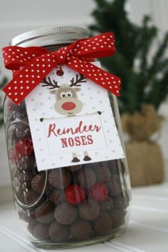 a glass jar filled with chocolate covered candies and a reindeer tag attached to it